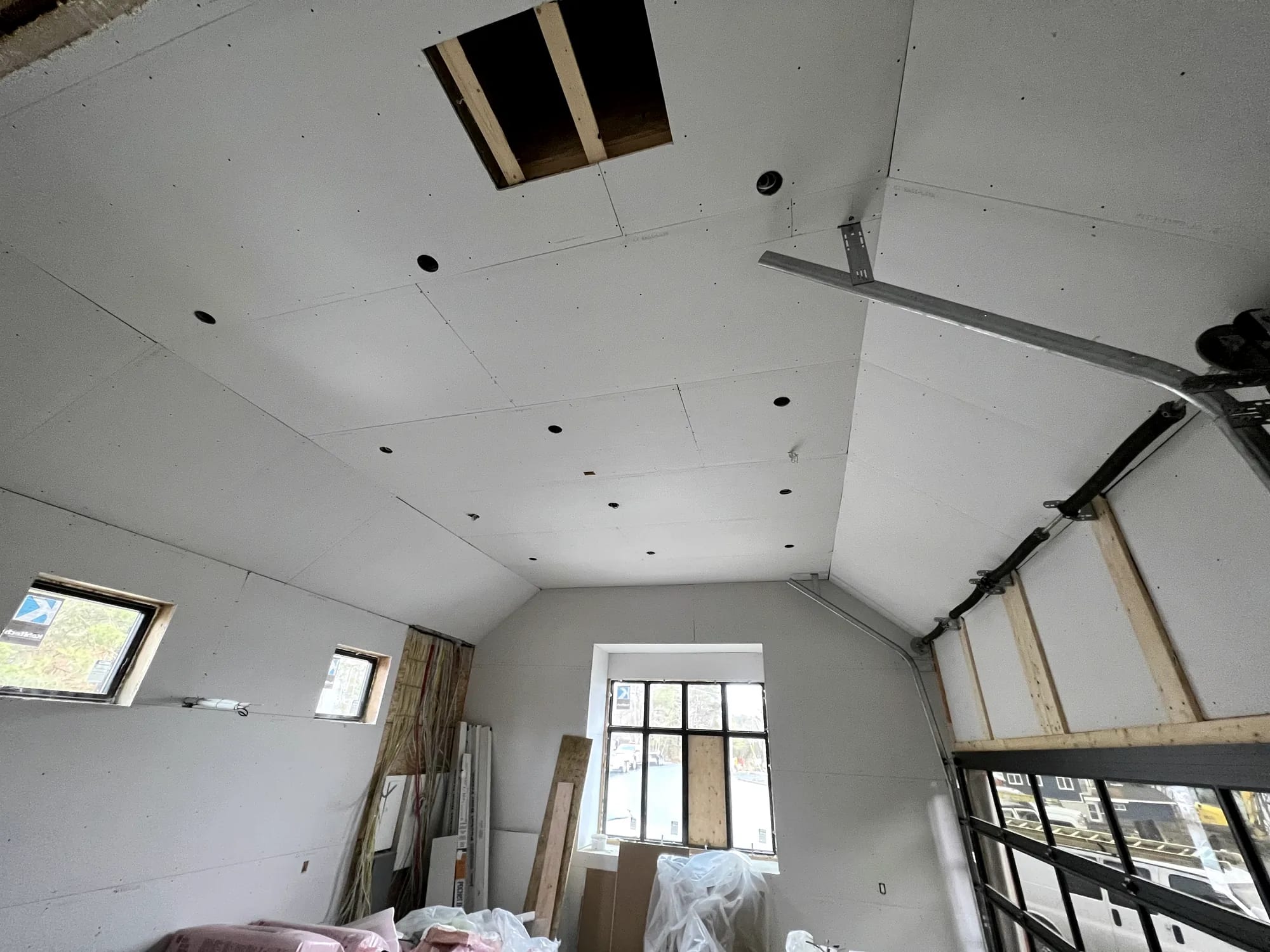 A boarded garage ceiling with recessed light openings cut clean and joints running straight