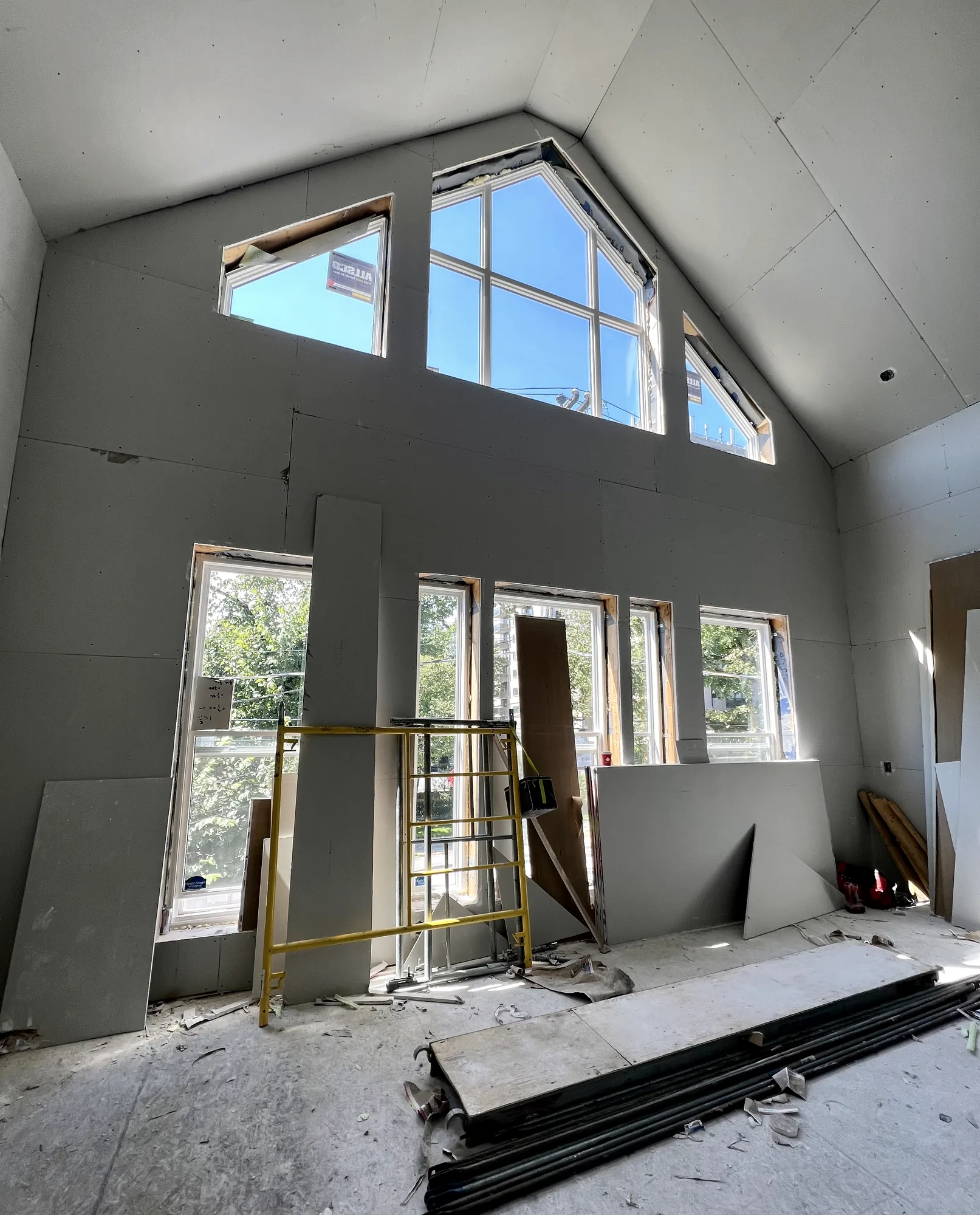A double-height great room in a Nova Scotia home with drywall installed across the gable end and vaulted ceiling, ready for taping