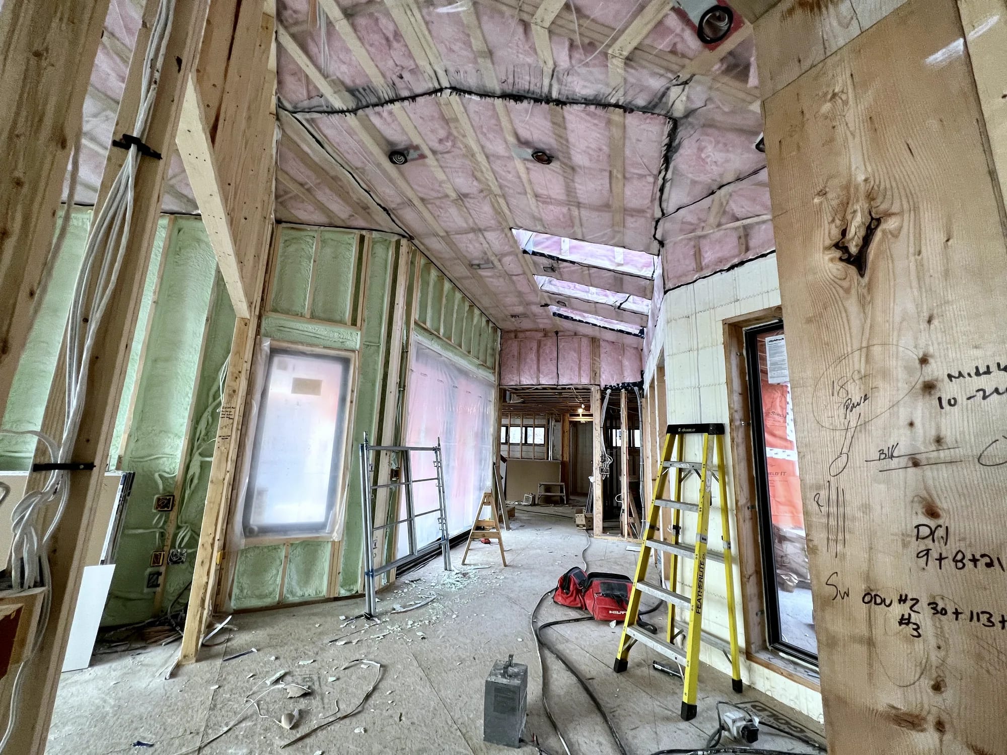 Batt insulation and sealed vapour barrier installed through a residential interior before drywall close-in