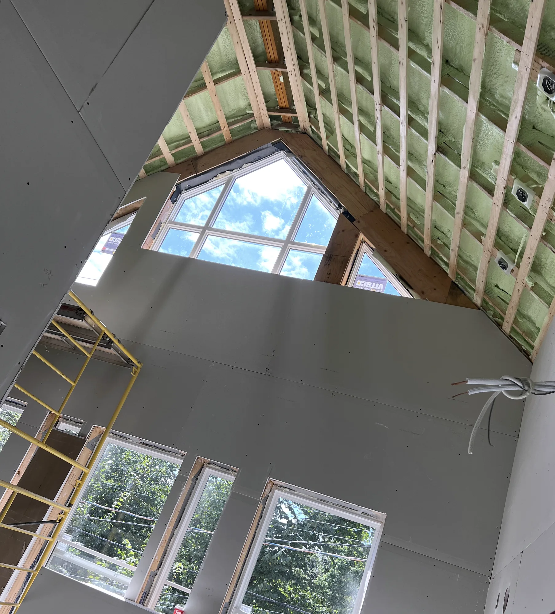 Full-height drywall installed on a vaulted room with insulated rafter bays still exposed above